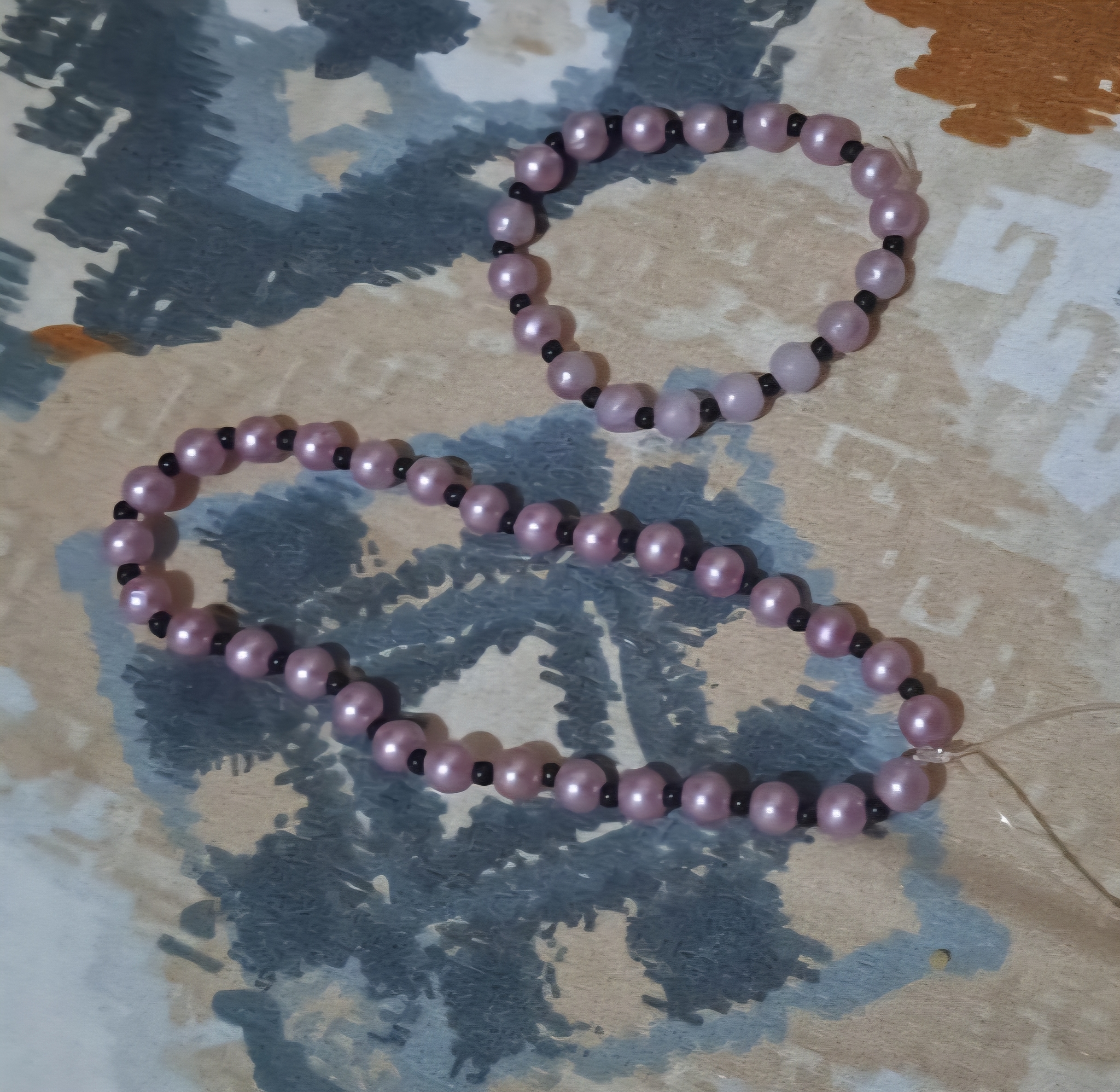 Deux bracelets de perles rose poudré nacrées rythmées de petites perles noires