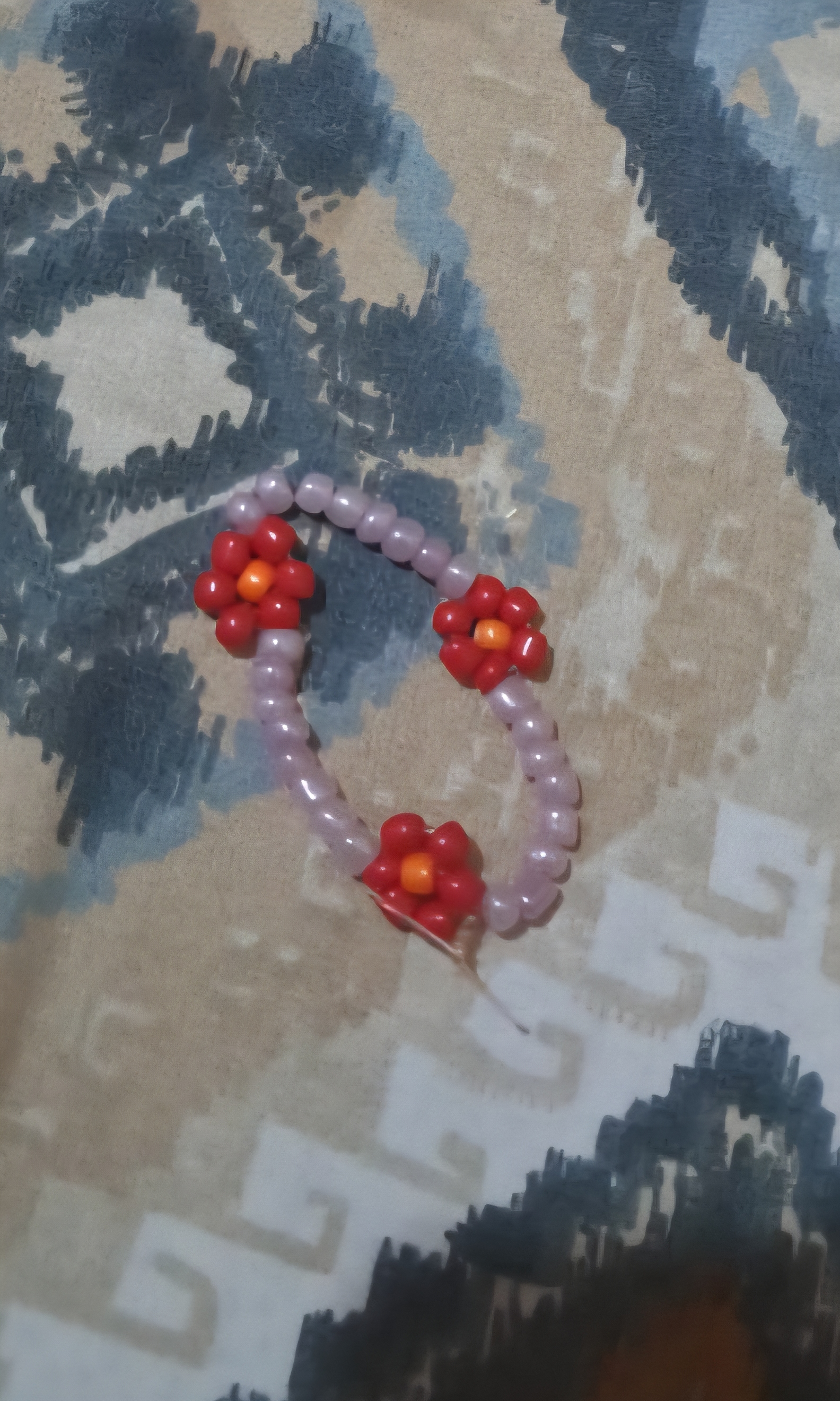 Bracelet de perles lilas orné de trois petites fleurs rouges