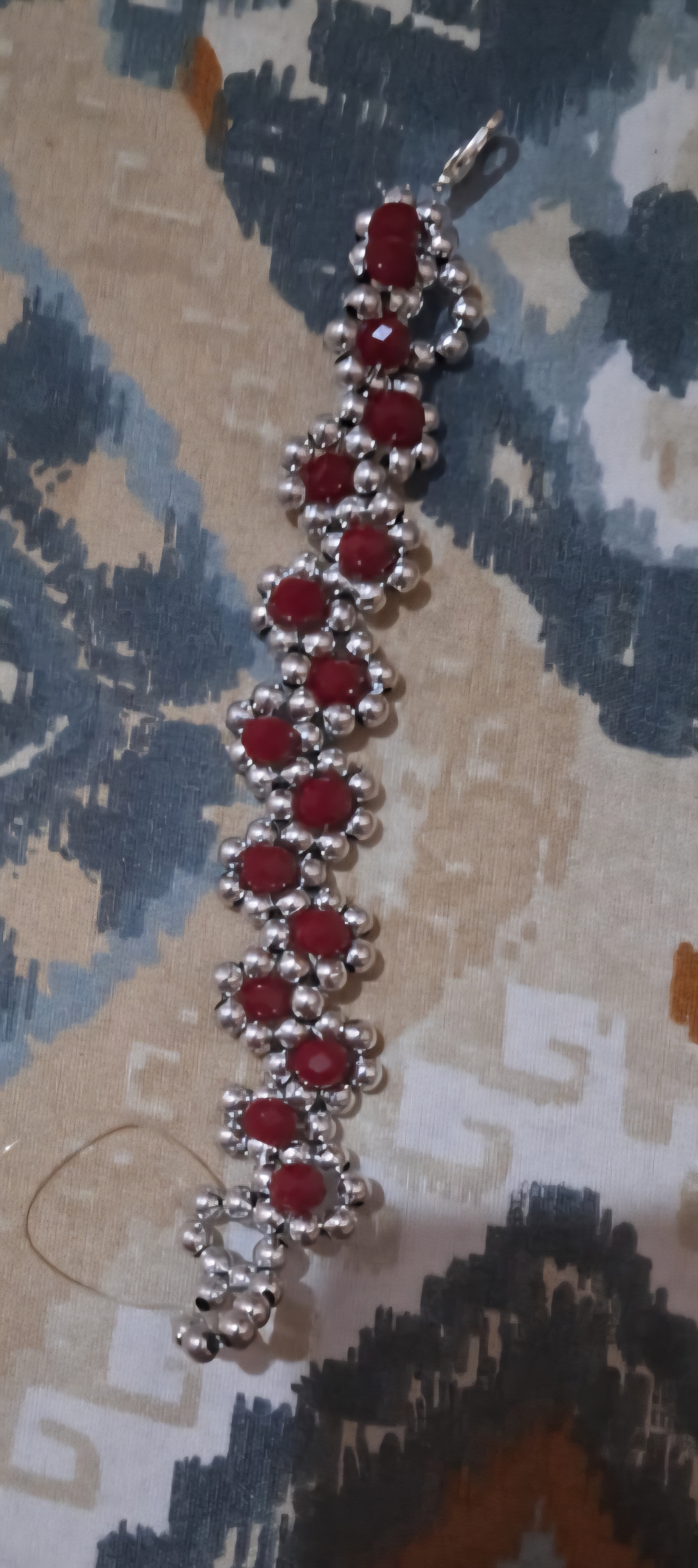 Bracelet tissé de perles argentées formant des fleurs au cœur rubis